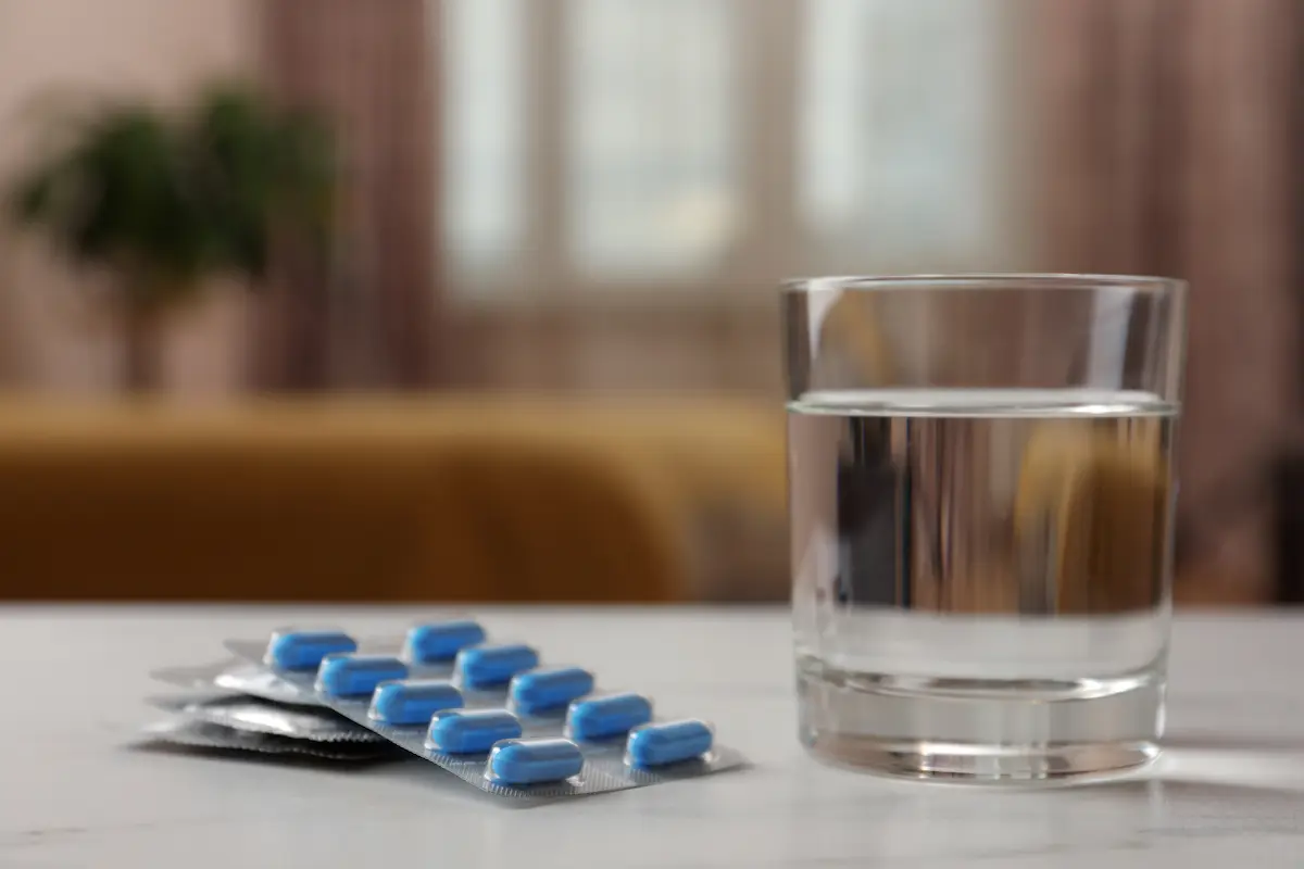 Blíster de analgésicos genéricos sin marca junto a un vaso de agua, ilustrando pastillas para el dolor de la muela